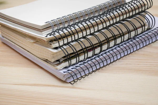 Pile of different notebooks lying on wooden table