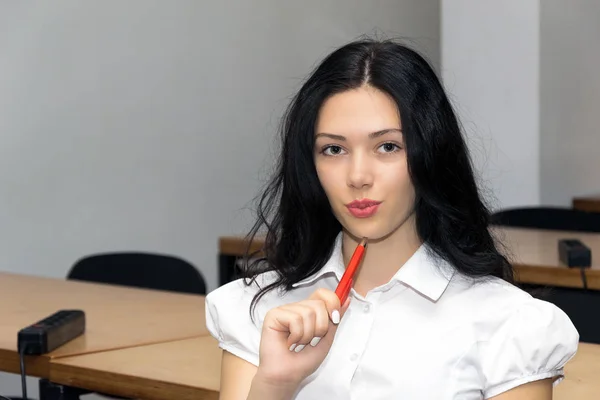 Девушка думает в классе, держит ручку. Школа, колледж, образование . — стоковое фото