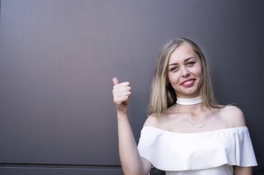 Uzağa işaret ve kamera gri arka plan karşı dururken bakarak genç kadın