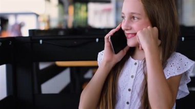 Kafede telefonda konuşuyor ve gülümseyen genç kız