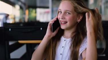 Kafede telefonda konuşuyor ve gülümseyen genç kız