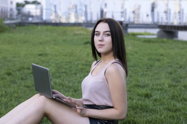 Tam uzunlukta portre çekici esmer kadın parkta oturan. Genç kadının boş zaman. Büyüleyici güzel pembe bluz modeli. Arka plan bulanık