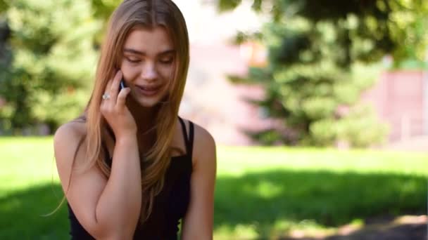Çekici bir genç sarışın kadın parlak bir gün batımı ışık telefon kullanarak görünümünü kapat. — Stok video