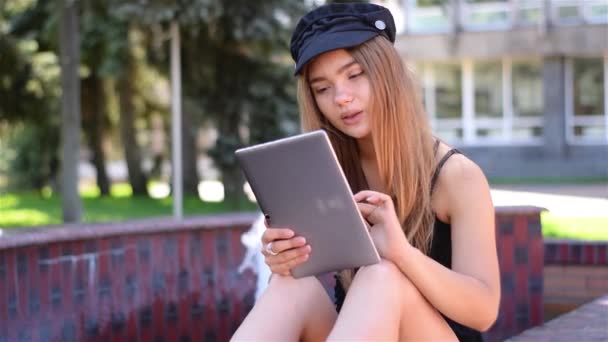 Jonge blonde zittend op bankje werken op tablet-pc. Vrouwelijke college studenten gebruik van draadloos internet in campus park. Mobiele communicatieconcept. — Stockvideo