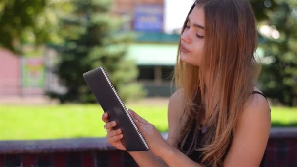 Mladá blondýnka sedí na lavičce pracuje na počítači tablet pc. Ženské college student pomocí bezdrátové připojení k Internetu v areálu parku. Mobilní komunikační koncept. — Stock video