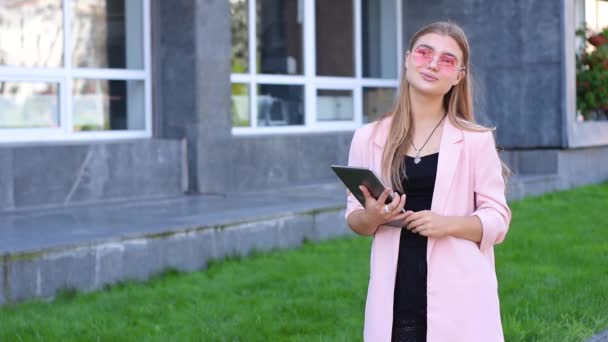 Młoda Blondynka w pracy komputera typu tablet w mieście. Kobieta za pomocą bezprzewodowego dostępu do Internetu na ulicy. Mobilna komunikacja koncepcja. — Wideo stockowe