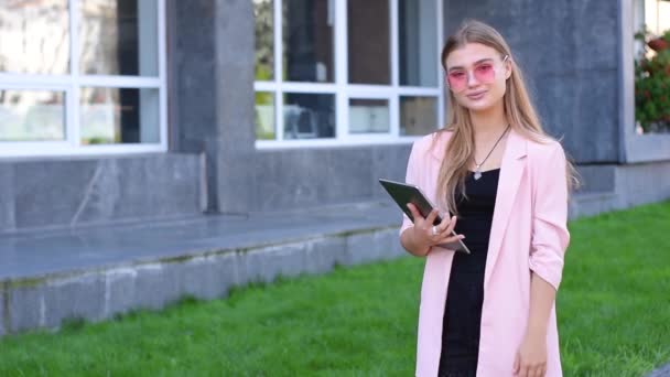 Joven rubia trabajando en la tableta PC en la ciudad. Mujer usando internet inalámbrico en la calle. Concepto de comunicación móvil . — Vídeo de stock