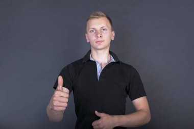 Karanlık bir arka planda başparmak yukarı genç casual adam