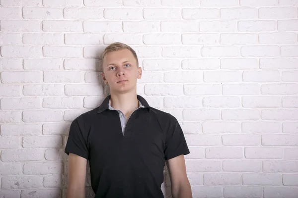 Man wearing blank black t-shirt. Brick white wall background — Stock Photo, Image