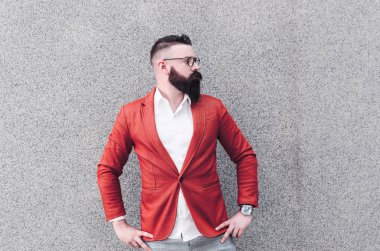 Gri duvar arka plan üzerinde duran, dergiye poz turuncu ceketli genç ve yakışıklı bir adam portresi