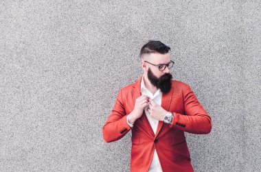 Gri duvar arka plan üzerinde duran, dergiye poz turuncu ceketli genç ve yakışıklı bir adam portresi