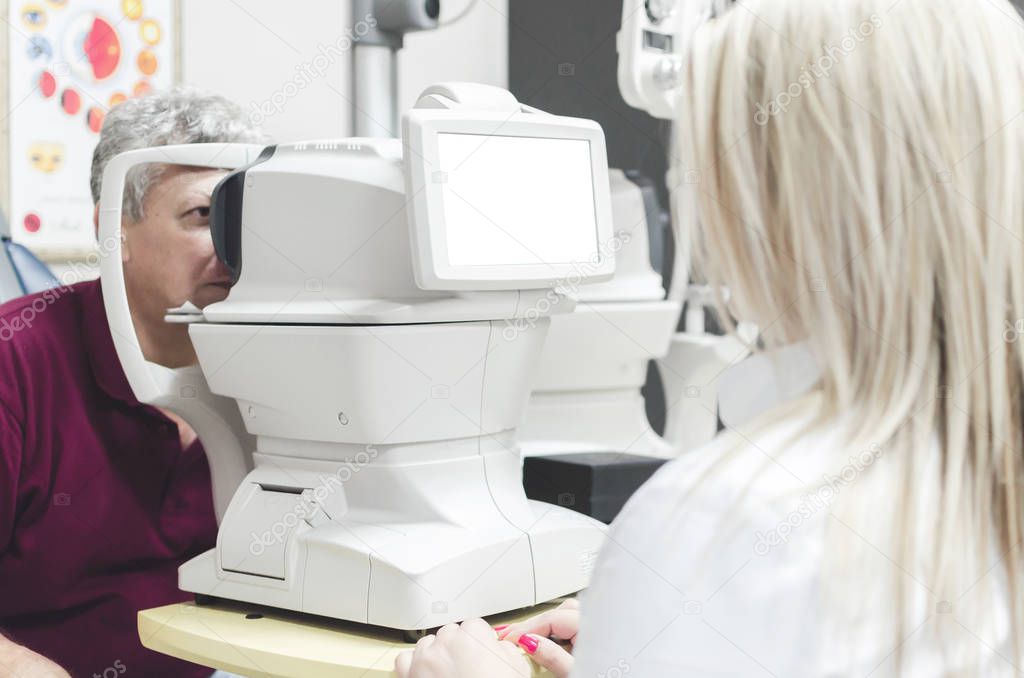 Man looking at refractometer eye test machine in ophthalmology, white empty screen