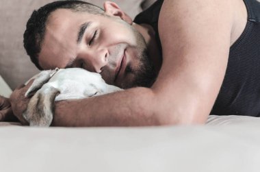 Genç adam köpek kapalı gözler ile sarılma Close-up