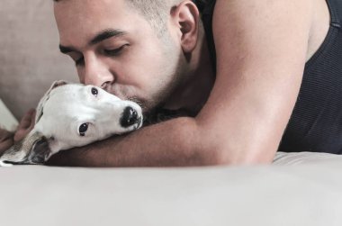 Genç adam köpek kapalı gözler ile sarılma Close-up