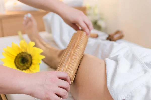 Close up of woman during spa anti cellulite massage with wooden rolling pin for anti cellulite