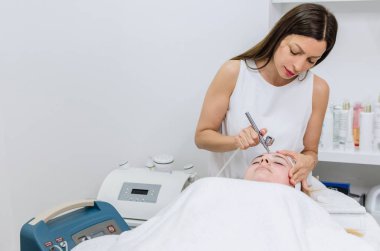 Beautiful Woman Receiving Dermaoxy treatment At Cosmetology Center. Girl Enjoying Skin Rejuvenation Procedure. Beauty Treatment Concept. clipart