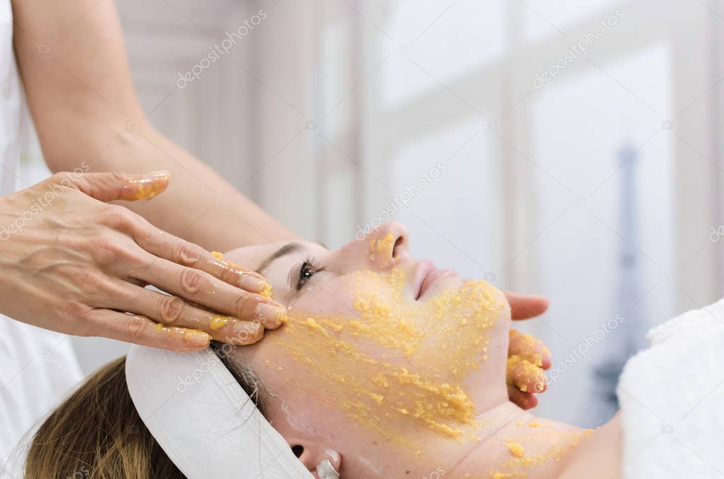Young beautiful woman receiving facial massage with peeling and spa treatment, close up