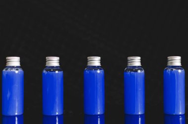 çok siyah arka plan, tıp kavramı, kozmetik, mavi sıvı ile önden görünümü küçük dolu cam şişe