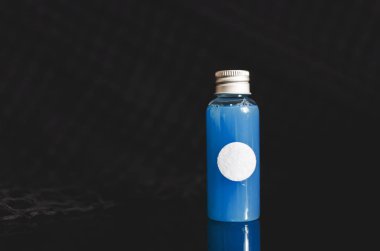 küçük dolu cam şişe mavi sıvı ve beyaz boşluk ile siyah arka plan, tıp kavramı üzerine önden görünüm