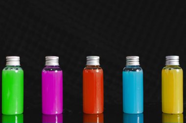 çok siyah arka plan, tıp kavramı, kozmetik, renkli sıvılar ile önden görünümü küçük dolu cam şişe