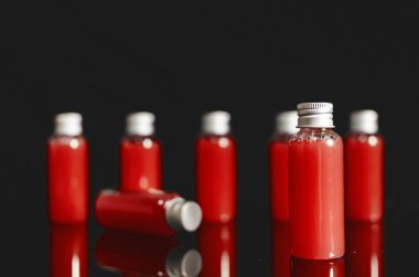 siyah arka plan, tıp kavramı, kozmetik, kırmızı sıvı ile çok küçük dolu cam şişe