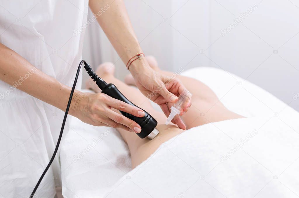 Close up of cosmetologist dropping vitamin oil on leg during mesotherapy at beauty salon.