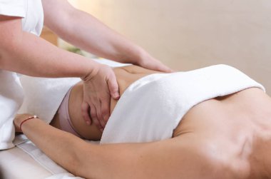 Genç kadın karin yaptığı masajdan sonra kapatın. Masör yapmak masaj mide güzellik spa salonu için.