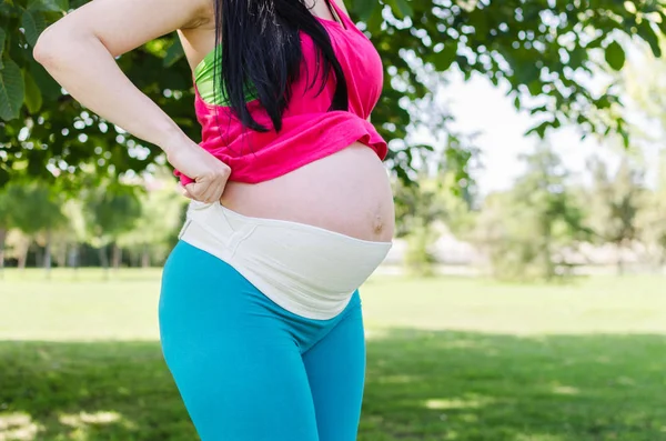 Крупный План Беременной Женщины Одевающей Материнский Пояс Открытом Воздухе — стоковое фото