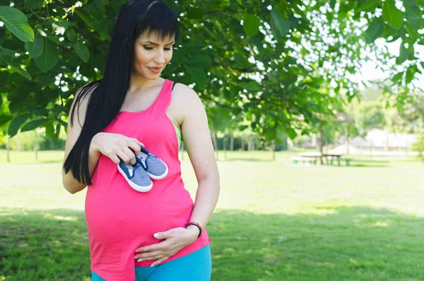 Hermosa Mujer Joven Embarazada Pie Naturaleza Con Pequeños Zapatos Bebé — Foto de Stock