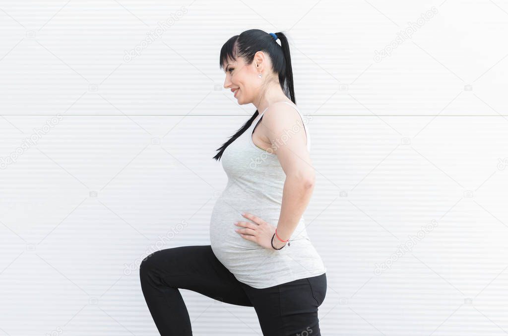 Portrait view of beautiful pregnant woman doing exercises outside.