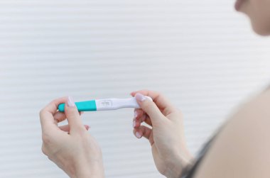 Genç hamile kadının elinde pozitif doğurganlık testi yakın çekim.