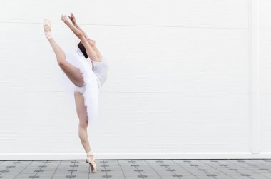 Güzel Klasik Bale dansçısı yan görünüm. Beyaz tutu pratik bale pozisyonda güzel zarif ballerine.