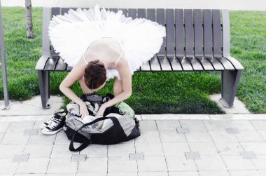 Sokakta, bankta oturmuş ve çantasını bir şey güzel genç kadın Bale dansçısı.