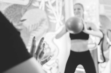 Genç kadının bazı egzersizleri pilates topu ile yapması onun üst düzey kadın trainter ile siyah beyaz görüntü.
