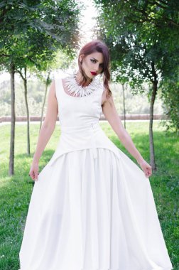 Güzel genç kadın dışında uzun beyaz elbisenin içinde poz önden görünümü.