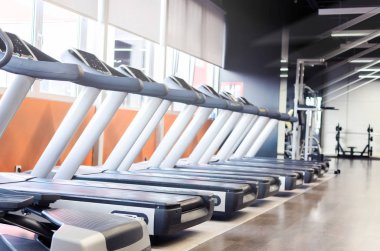 Boş spor salonu ve modern koşu bandı içindeki görüntü.