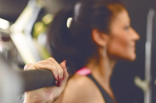 Woman with barbell doing squats at gym.