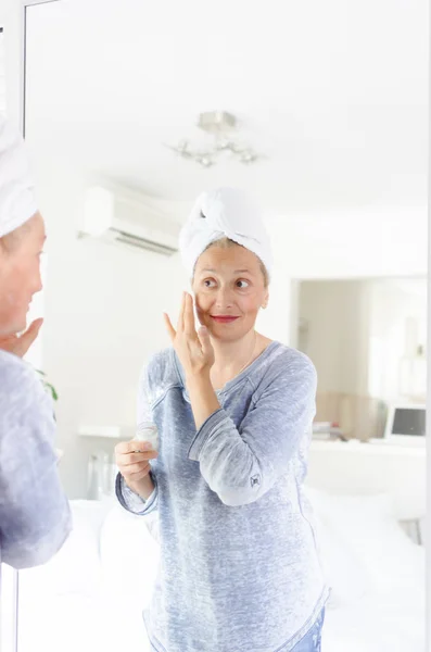 Femeie Bătrână Fericită Care Aplică Cremă Îmbătrânire Lângă Oglindă — Fotografie, imagine de stoc