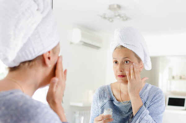 Gorgeous senior woman applying anti-aging cream on her face.