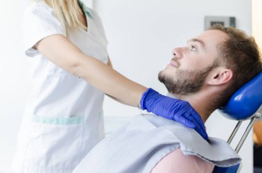 Sandalyenin üstüne yalan dişçi ofisinde, erkek genç hastaya portresi.