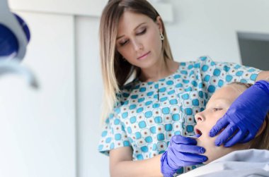 Female dentist taking tooth print of young girl. clipart