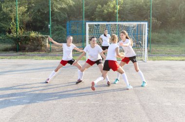 Female handball players are playing game outside. clipart