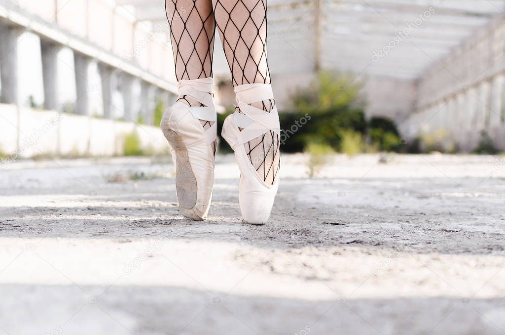 Close up of ballerina's legs, she is posing outside wearing pointe shoes.