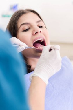 Kadın dişçi hastalarının dişlerinde çalışıyor..