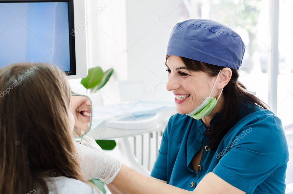 Portrait of female smiling dentist, while having consultations with young patient.