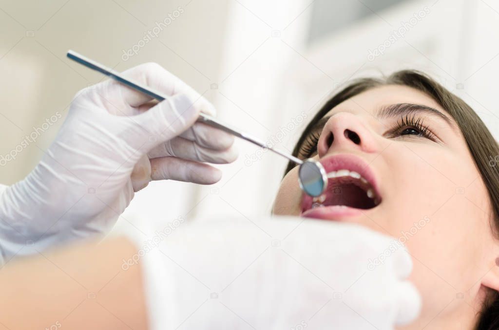 Close up of dentist examining patient's teeth in clinic.