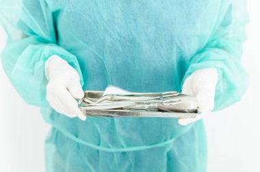 Bir tepsi steril diş araçları ile tutarak dişçi resim kırpılmış.