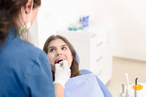 Young female patient sitting on chair at dental clinic, having control of teeth.