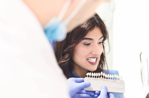 Портрет молодой красивой женщины, выбирающей цвет зубов у стоматолога
 