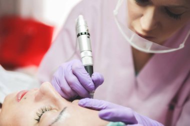 Güzellik salonu bulunan genç bayan hasta, kalıcı makyaj yaparken profesyonel güzellik uzmanı, yakın çekim